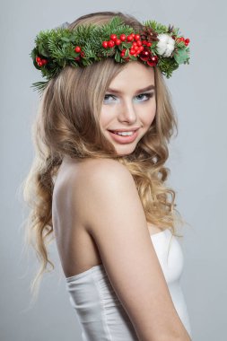 Uzun dalgalı sarı saçlı ve makyajlı bir kadın. Beyaz arka planda kışın gülümseyen komik genç bayan.