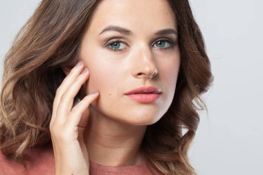 Açık tenli, makyajlı ve dalgalı kahverengi saçlı güzel bir kadın. Doğal makyajlı bir bayan. Yüzünü kapat.