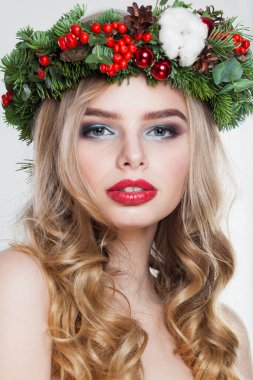 Beyaz stüdyo arka planında uzun dalgalı saçları, makyajı ve renkli kış süslemeleri olan genç model kadın, moda güzelliği portresi.