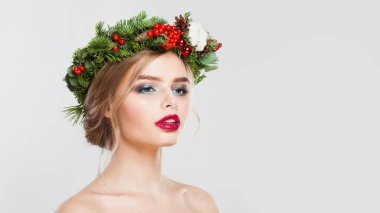 Beyaz stüdyo arka planında uzun dalgalı saçları, makyajı ve renkli kış süslemeleri olan şık model kadın, moda güzellik portresi.