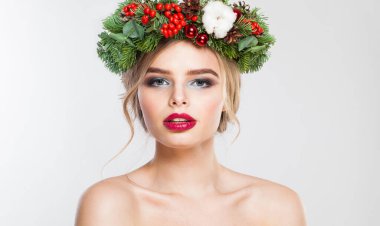 Beyaz stüdyo arka planında uzun dalgalı saçları, makyajı ve renkli kış süslemeleri olan güzel model kadın, moda güzelliği portresi.