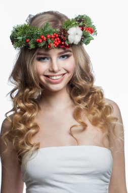 Beyaz stüdyo arka planında uzun dalgalı saçlı, makyajlı ve renkli doğal kış dekorasyonlu model kadın, moda güzellik portresi.