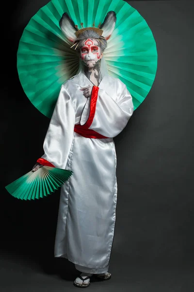 Creative model woman with makeup wearing mask and stage kimono costume. Halloween, carnival, performance and theater concept