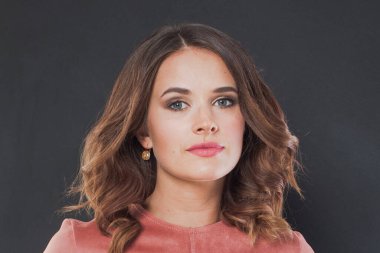 Dalgalı kahverengi saç stili ve beyaz arka planda makyajı olan muhteşem bir kadın.