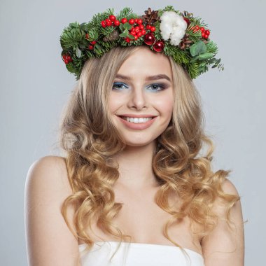 Noel kadını gülümsüyor. Beyaz arka planda uzun dalgalı sarı saçlı güzel bir bayan model, moda güzellik stüdyosu portresi