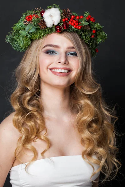 Christmas beauty woman. Happy young model with makeup, clean fresh skin, wavy blonde hair, perfect smile and Xmas New Year decoration