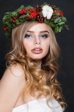 Kameraya bakan sevimli genç bir kadın, moda güzellik stüdyosu portresi. Uzun dalgalı sarı saçlı, siyah arka planda poz veren güzel bir bayan model.