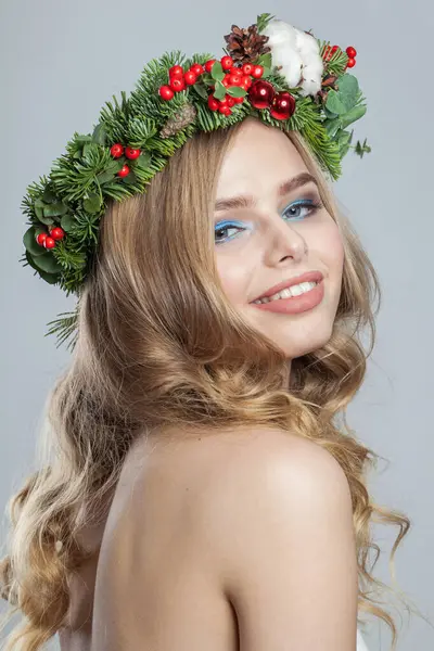 Christmas beauty woman. Perfect young model with makeup, clean fresh skin, wavy blonde hair, perfect smile and Xmas New Year decoration