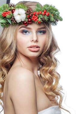 Parti makyajlı, uzun sarı kıvırcık saçlı ve beyaz arka planda Noel dekoru olan oldukça sağlıklı genç bir kadın. Noel güzeli