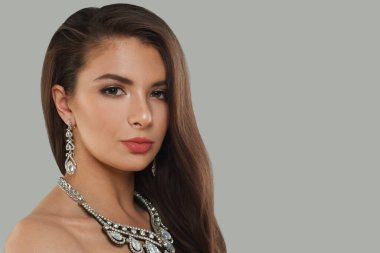 Gri arka planda uzun, siyah dalgalı saçları ve makyajı olan mükemmel bir esmer kadın. Güzel yüz yakından, stüdyo portresi.