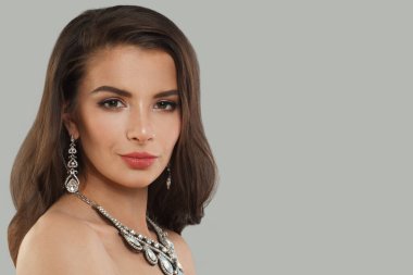 Gri arka planda uzun, siyah dalgalı saçları ve makyajı olan güzel bir kadın. Güzel yüz yakından, stüdyo portresi.