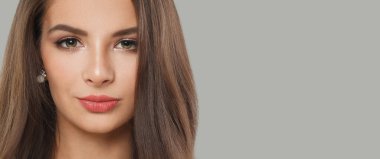 Gri arka planda uzun siyah dalgalı saçları ve makyajı olan hoş bir esmer kadın. Güzel yüz yakından, stüdyo portresi.