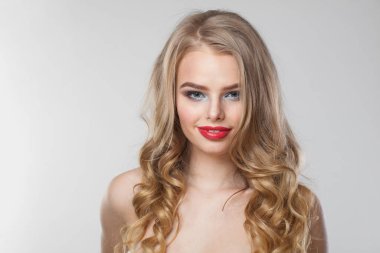 Güzel genç bayan model portresi. Beyaz arka planda uzun dalgalı saçlı, makyajlı ve temiz tenli sarışın kadın.