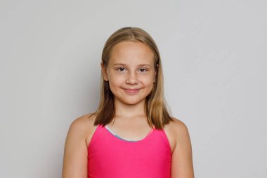 Gri stüdyo arka planında kameraya bakan güzel bir genç kız.