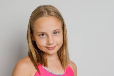 Gri stüdyo arka planında kameraya bakan hoş bir genç kız.