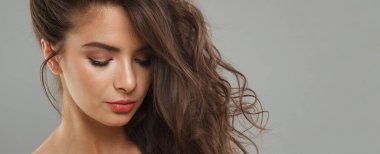 Koyu renk, sağlıklı saç stili, yeni cilt ve gri arka plandaki kameraya bakan modaya uygun makyaj modeli. Esmer kadın portresi