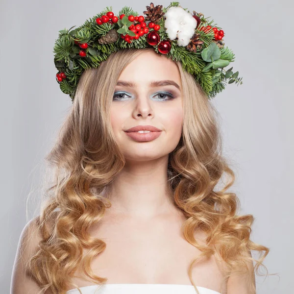 Christmas beauty woman. Cute model with makeup, clean fresh skin, wavy blonde hair and Xmas New Year decoration