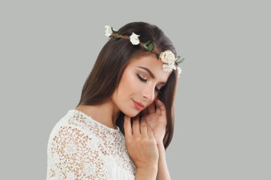 Gri arka planda uzun, siyah dalgalı saçları ve makyajı olan esmer bir gelin. Güzel yüz yakından, stüdyo portresi.