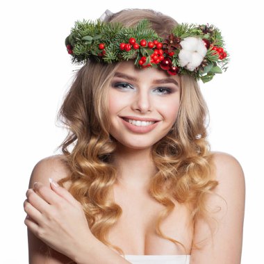 Duygusal açıdan sağlıklı, parti makyajlı, uzun kıvırcık saçlı ve beyaz arka planda Noel dekoru olan genç bir kadın. Noel güzeli