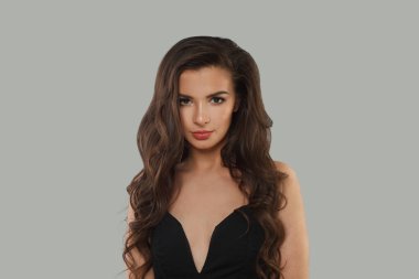 Koyu sağlıklı saç stili, yeni cilt ve gri arka plandaki kameraya bakan modaya uygun bir model. Esmer kadın portresi