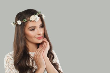Esmer, sağlıklı bir saç stili, temiz bir ten ve gri arka plandaki kameraya bakan modaya uygun bir model. Esmer kadın portresi