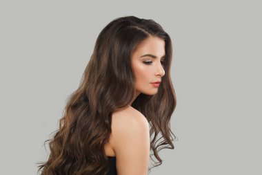 Güzel görünümlü esmer moda güzellik portresi. Gri stüdyo arka planında uzun, siyah, sağlıklı saçları ve taze cildi olan genç model bir kadın.