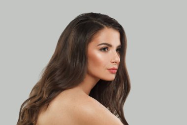 Çekici esmer moda güzellik portresi. Gri stüdyo arka planında uzun, siyah, sağlıklı saçları ve taze cildi olan genç model bir kadın.