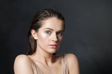 Sağlıklı, ıslak ciltli, koyu renk saçlı, kameraya bakan güzel bir kadın modeli. Moda güzelliği portresi.