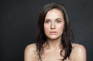 Çekici bir kadın model, sağlıklı ıslak ten ve koyu renk saç, kameraya bakıyor, moda güzelliği portresi.
