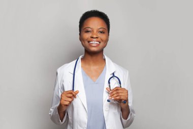 Gri arka planda duran mutlu kadın doktor.