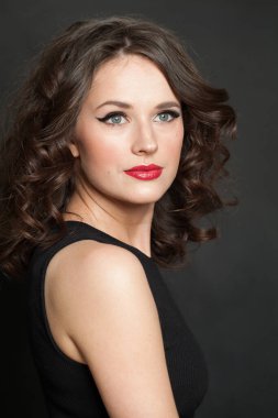 Dalgalı saç stili, sağlıklı cildi ve mükemmel makyajı olan, stüdyo moda portresi olan oldukça genç, çekici, modaya uygun, esmer bir kadın.