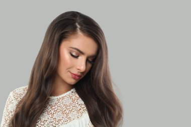 Mükemmel sağlıklı bir cilde ve beyaz arka planda uzun saçlara sahip şık bir genç kadın. Stüdyo moda portresi.