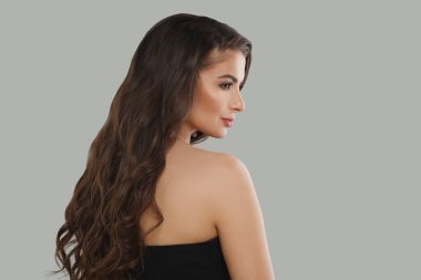 Güzel, genç, esmer, uzun, sağlıklı saçlı, beyaz arka planda taze cilt ve makyajlı bir kadın.