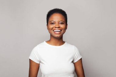 Gülen mutlu kadın gülümsüyor ve beyaz stüdyo duvarına karşı eğleniyor. Duygusal ifade portresi.