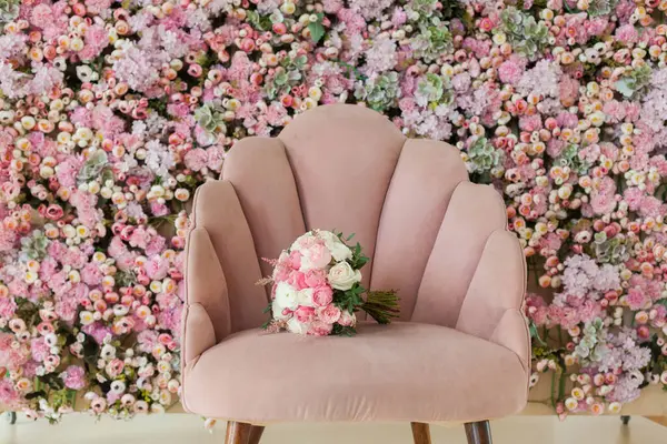 Flower bouquet on pink armchair against floral blossom background