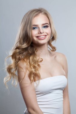 Beyaz arka planda izole edilmiş neşeli, sağlıklı sarışın model. Makyajlı, temiz tenli ve dalgalı sarı saçlı bir kadın. 