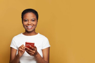 Telefonuyla mesaj atan mükemmel bir genç kadın. Akıllı telefon kullanan, mesajlaşan ya da sosyal ağları tarayan mutlu model öğrenci