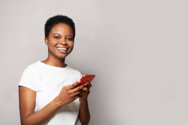 Neşeli genç bir kadın telefonuyla mesaj atıyor. Akıllı telefon kullanan, mesajlaşan ya da sosyal ağları tarayan mutlu model öğrenci