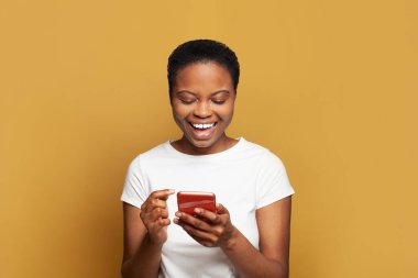 Telefonuyla mesaj atan heyecanlı genç bir kadın. Akıllı telefon kullanan, mesajlaşan ya da sosyal ağları tarayan mutlu model öğrenci