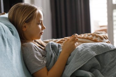 Evde akıllı telefon kullanan güzel bir kız. Rekabetçi bir video oyununda oynayan ya da akıllı telefondan sohbet eden şirin bir çocuğun portresi 