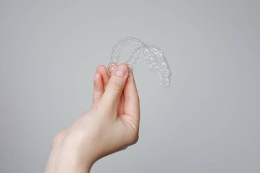 Ortodontik tedavide kullanılabilir şeffaf görünmez diş hizalayıcıları ya da diş telleri olan insan eli