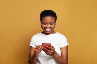 Pozitif genç bir kadın telefonuyla mesaj atıyor. Akıllı telefon kullanan, mesajlaşan ya da sosyal ağları tarayan mutlu model öğrenci