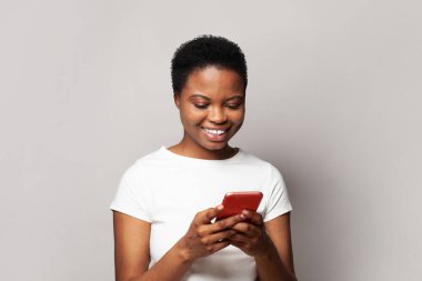 Güzel genç bir kadın telefonuyla mesaj atıyor. Akıllı telefon kullanan, mesajlaşan ya da sosyal ağları tarayan mutlu model öğrenci