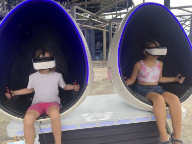 Fütürist VR kulaklıklı iki kız sanal gerçeklik kabininde oynuyor ve eğleniyorlar.