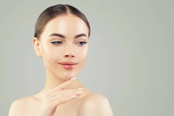 迷人的女人面部抬起抗衰老的线条在年轻的女性脸上 图形线条显示面部提升对皮肤的影响 整形外科 美容和按摩概念 图库照片