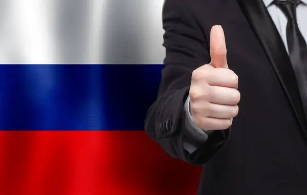 Russian concept. Businessman showing thumb up on the background of flag of Russia