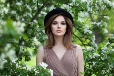 Taze tenli, makyajlı ve açık havada kahverengi dalgalı saçlı çekici bir kadın.