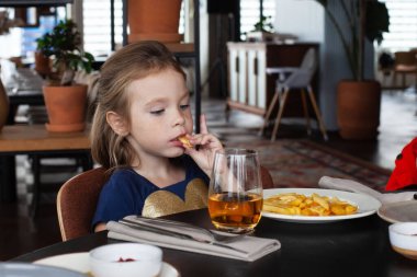 Küçük kız restoranda yemek yiyor.