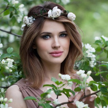 Makyajlı, temiz tenli, sağlıklı saç stili olan ve çiçek parkında gülümseyen muhteşem bir kadın model. Doğal güzel kadın portresi.