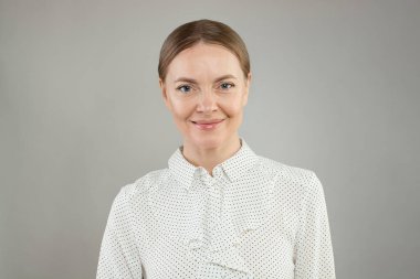 Başarılı gülümseyen olgun bir kadın stüdyo resmi.